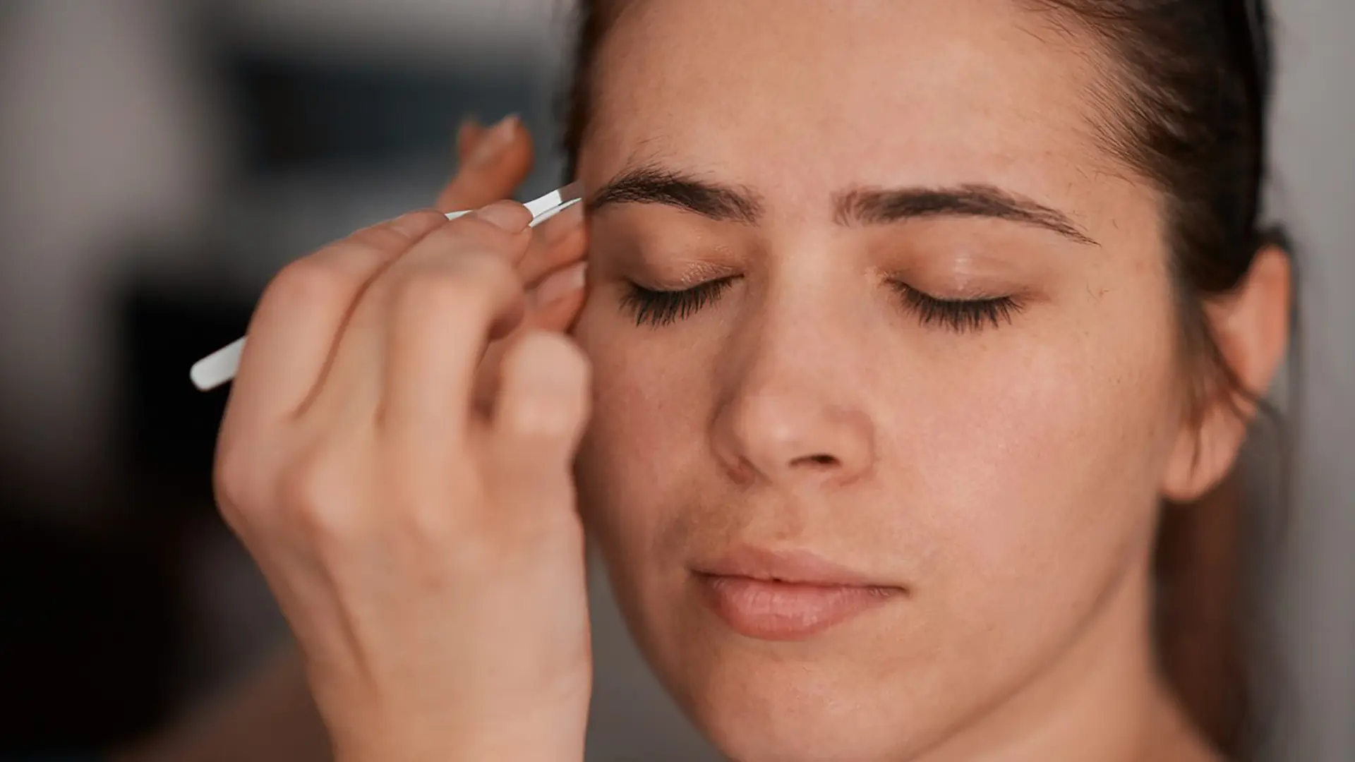 Frau beim Augenbrauen zupfen