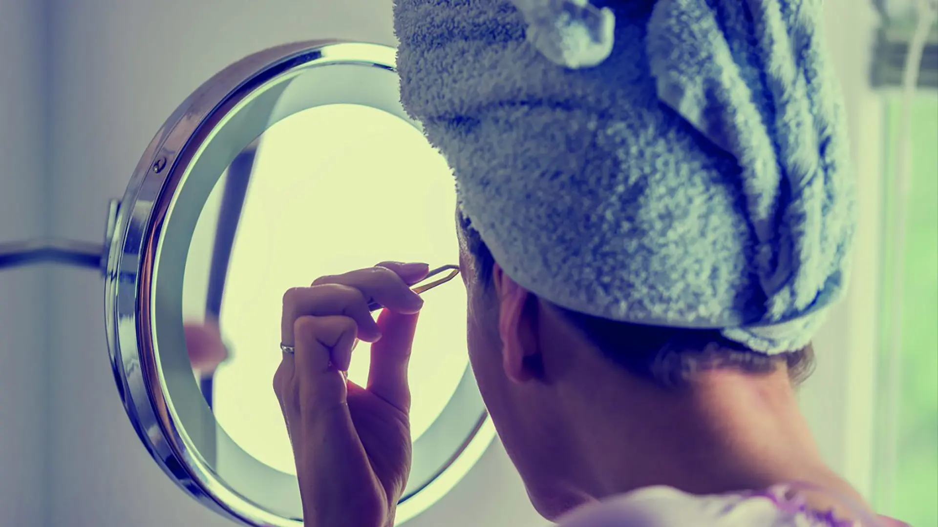 Frau mit Handtuch Turban beim Augenbrauen zupfen