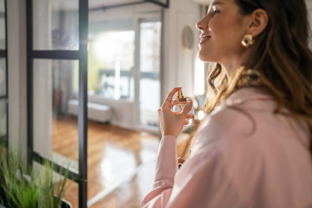 Lächelnde Frau die sich Parfum aufträgt
