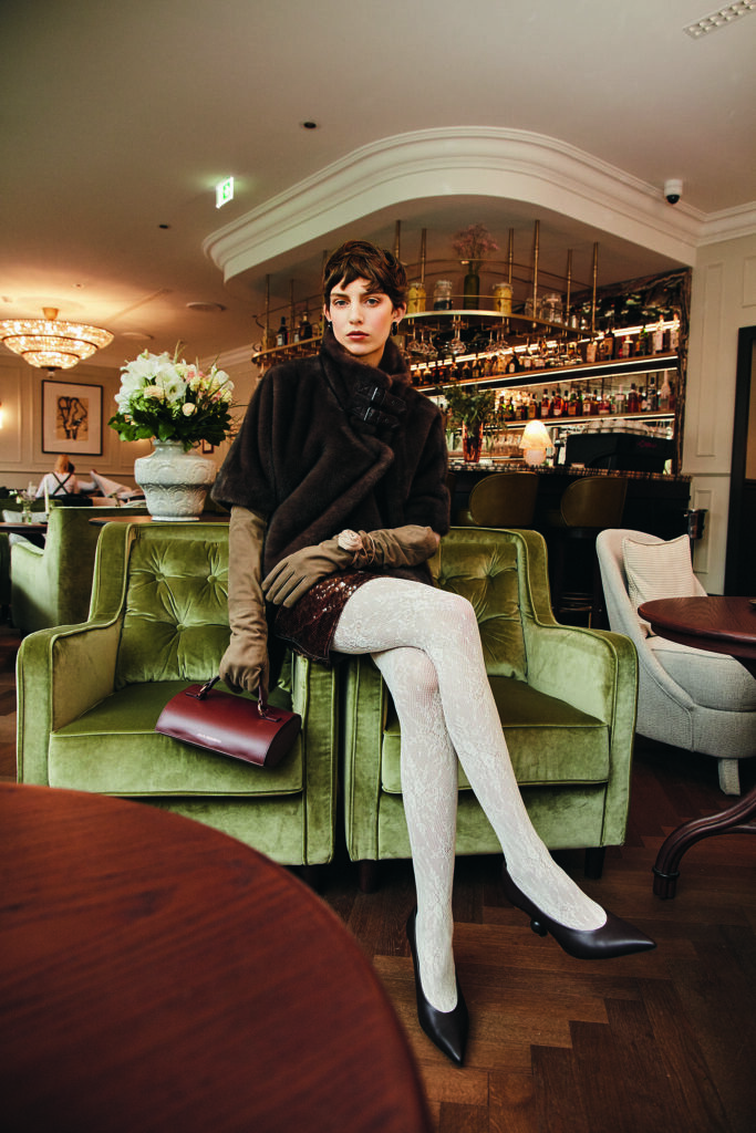 Frau im glamourösen Look auf einem Stuhl sitzend