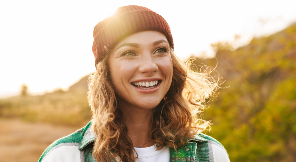 Junge Frau mit Mütze die in der Natur spaziert