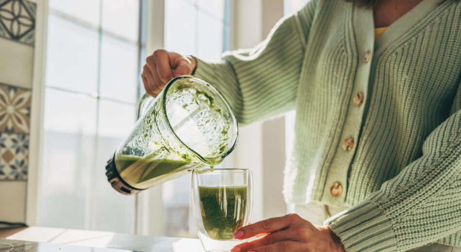 Frau die sich einen grünen Smoothie in ein Glas leert