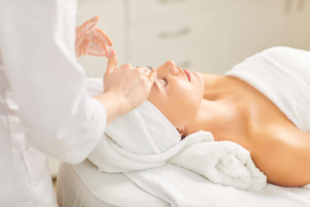 Eine Kosmetikerin massiert einem Mädchen im Kosmetikstudio das Gesicht.