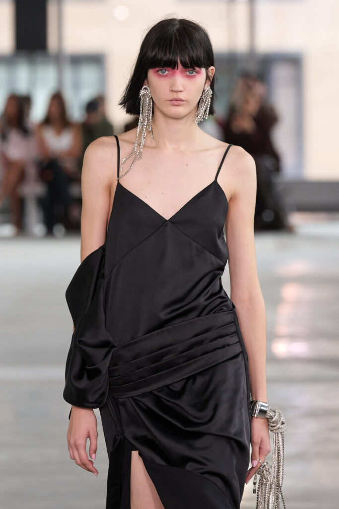 Model mit kurzen schwarzen Haaren, orange geschminkten Augen und schwarzem Kleid, Style Area