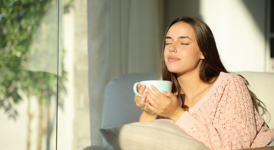 Frau die entspannt zu Hause einen Tee trinkt