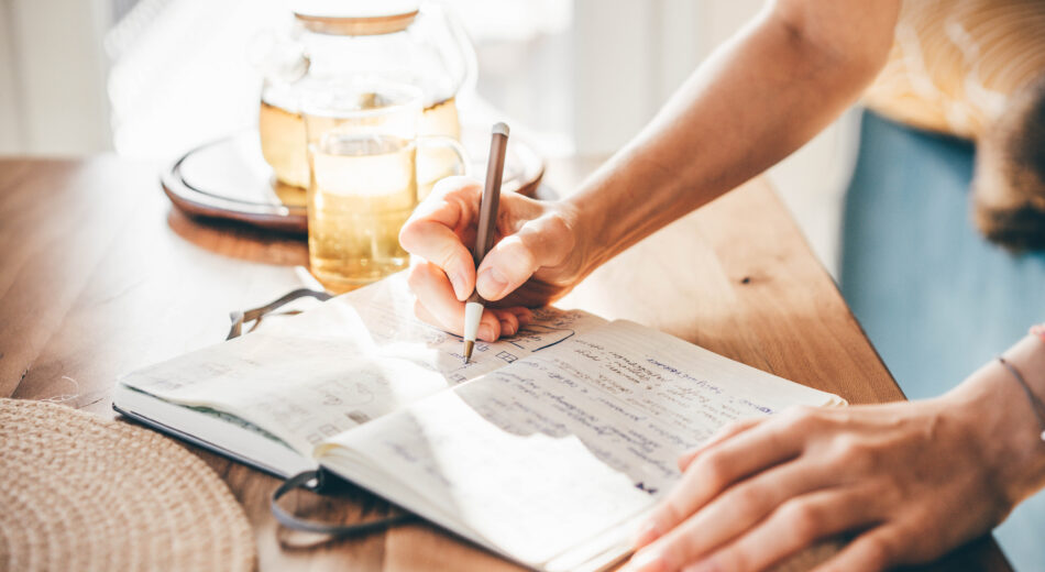 Eine Frau schreibt in ein Notizbuch.