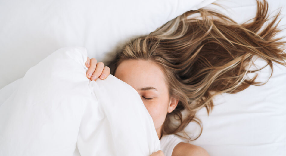 Eine junge Frau mit langen Haaren wachte zu Hause im Bett auf.
