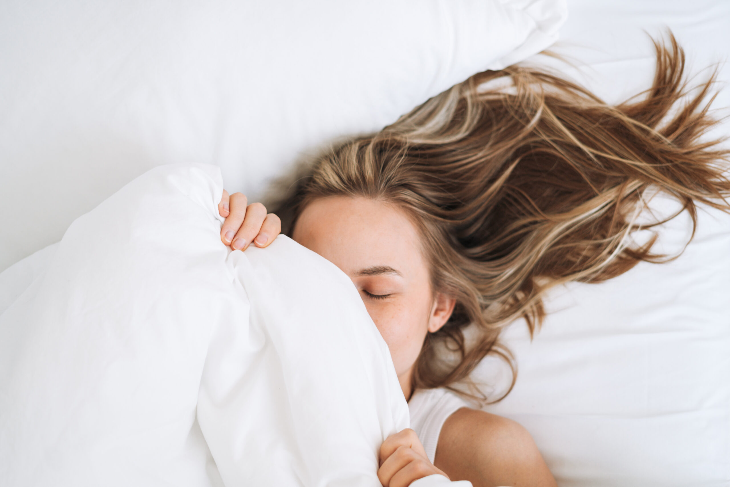 Eine junge Frau mit langen Haaren wachte zu Hause im Bett auf.