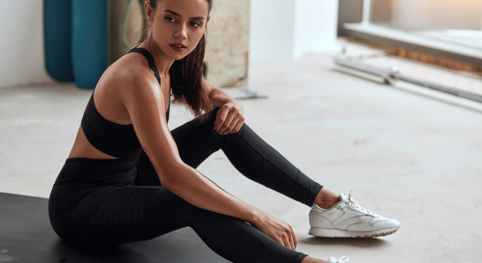 Porträt einer müden Frau, die im Fitnessstudio sitzt