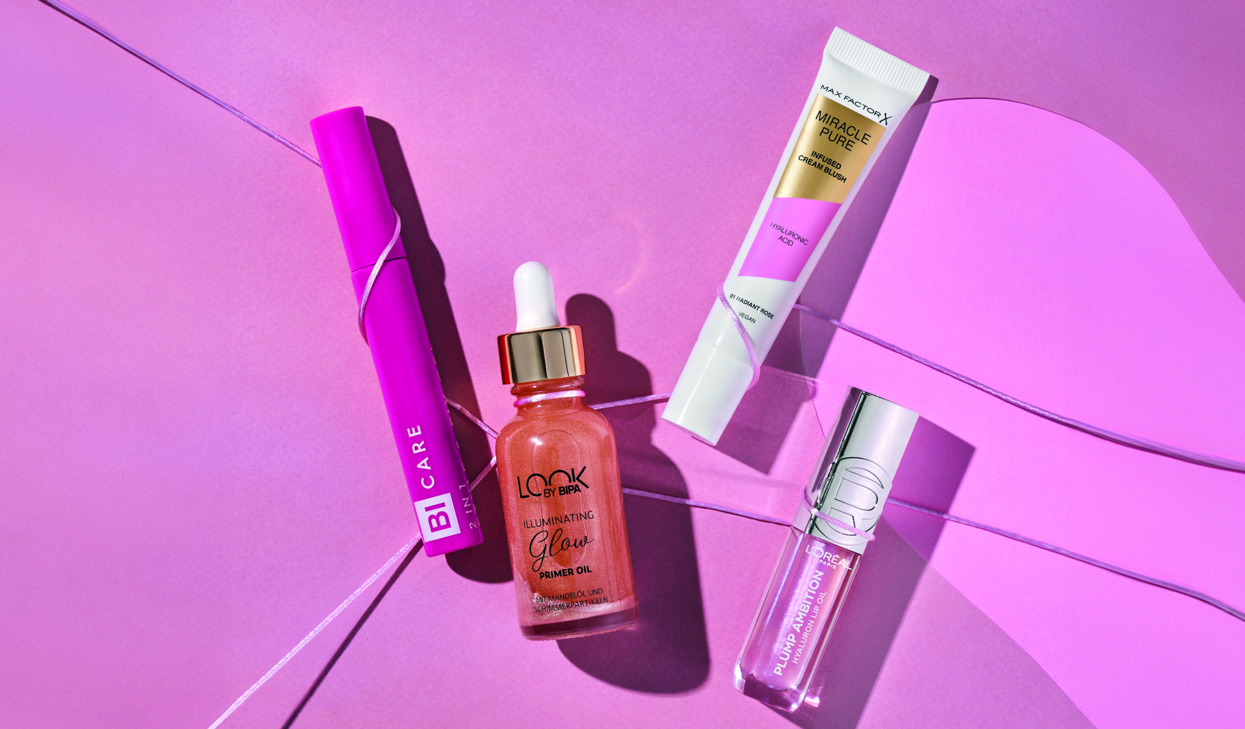 Freisteller diverser Make-Up Produkte auf pinkem Hintergrund