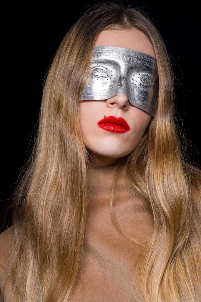 Model mit honigfarbenen langen Haaren, einer silbernen Maske über den Augen und roten Lippen, Kollektion Matieres Fecales