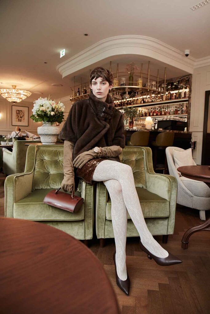 Frau im glamourösen Look auf einem Stuhl sitzend