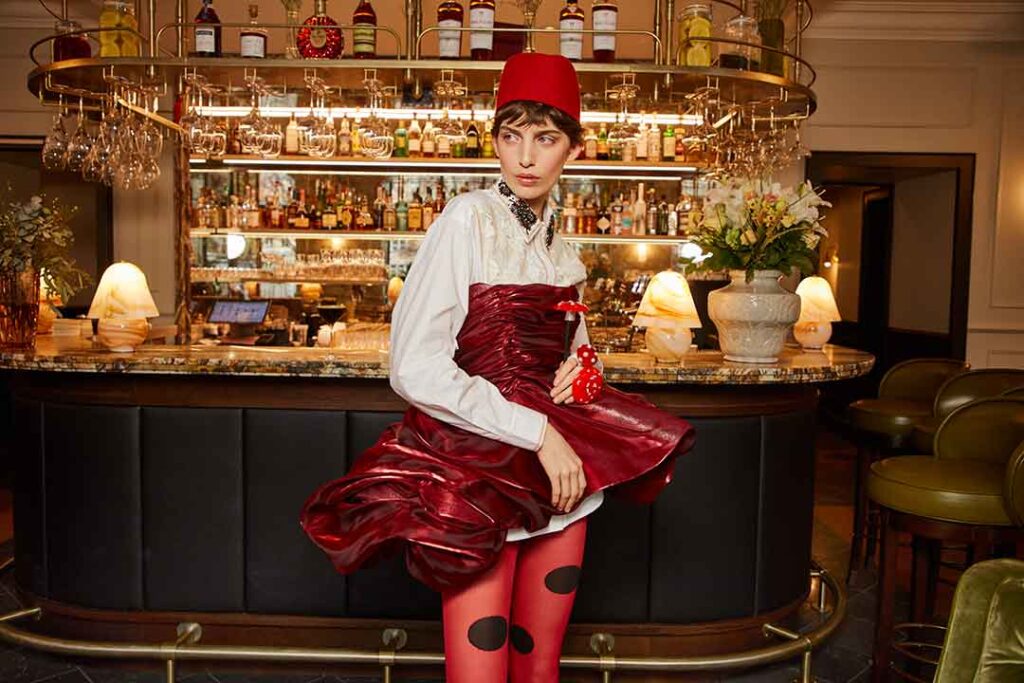 Frau in glamourösem Metallic-Kleid vor einer Bar posierend
