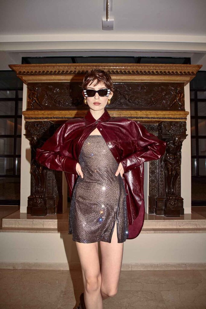 Frau im Mini-Glitzer-Dress mit metallic Overshirt und dunkler Sonnenbrille